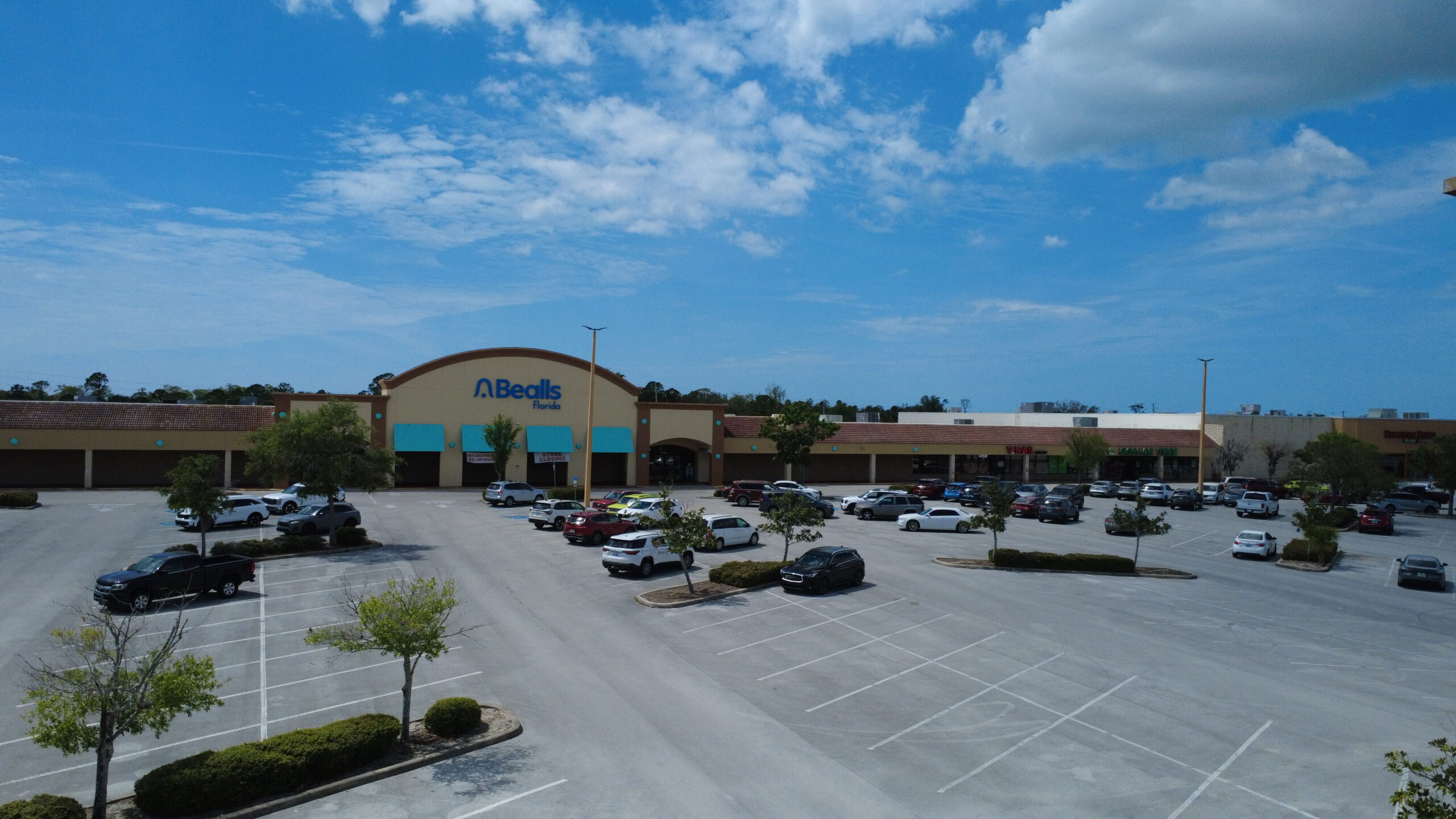 Aerial view of a Bealls store in Florida, showcasing a partially filled parking lot and clear blue skies, indicating a sunny day.